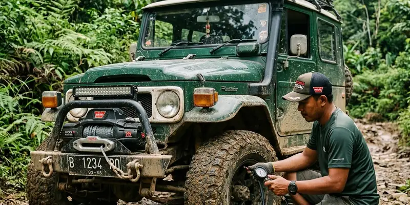 Seorang pengemudi offroad sedang mengecek tekanan ban dan perangkat winch kendaraan